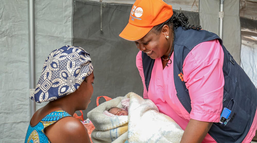 A midwife hands a mother her newborn. 